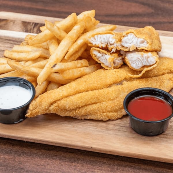 Fried fish fillets and french fries with dipping sauces on a wooden board.