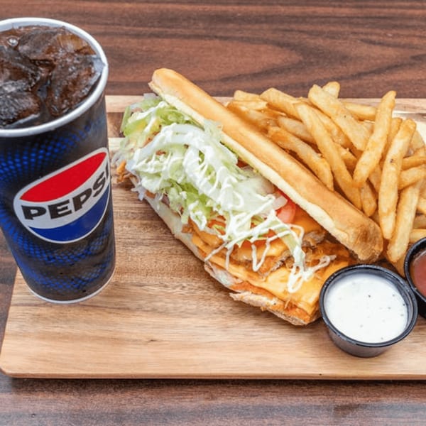 Jordan's Fish and Chicken sub sandwich with fries, two dipping sauces, and a Pepsi on a wooden board.