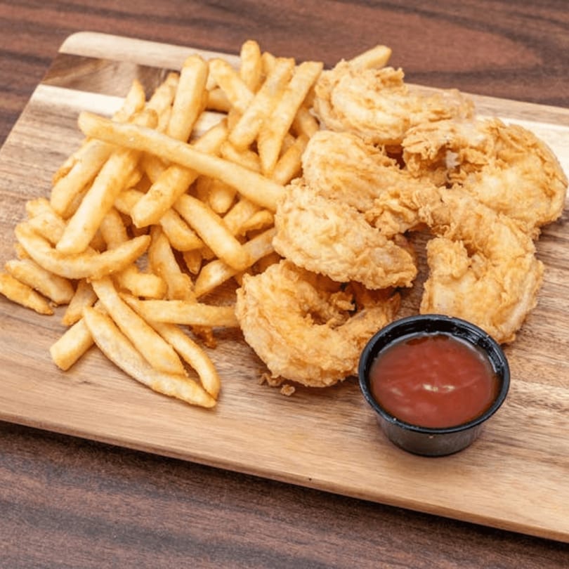 Golden-brown fried shrimp and french fries with a side of ketchup on a wooden board.