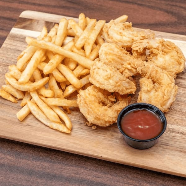 Golden-brown fried shrimp and french fries with a side of ketchup on a wooden board.